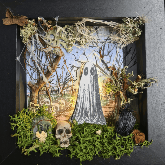 Completed 3D mixed media art scene from “The Little Haunting” kit, featuring a glowing ghost, sculpted tombstone, moss, fairy lights, and gothic frame.
