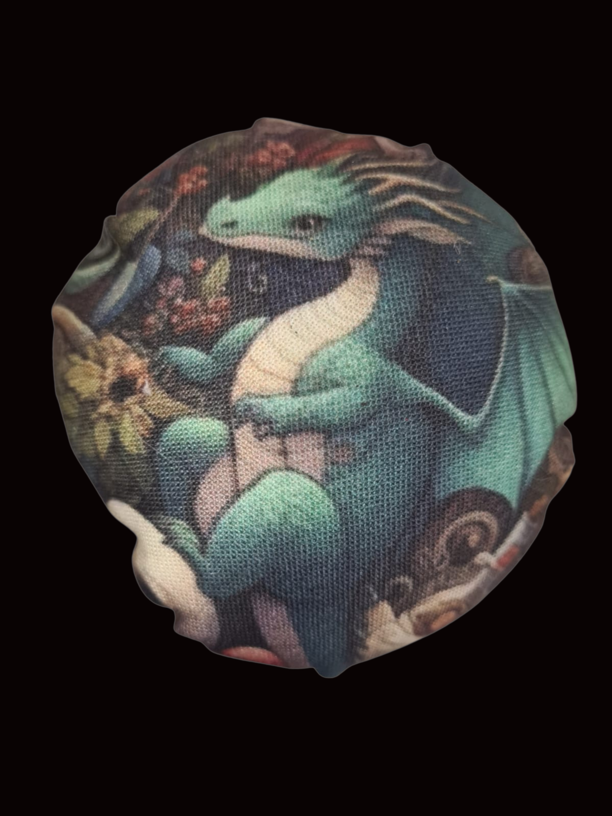 Macro close-up of Potion Keeper dragon cartoon fabric on a shroom pin cushion.